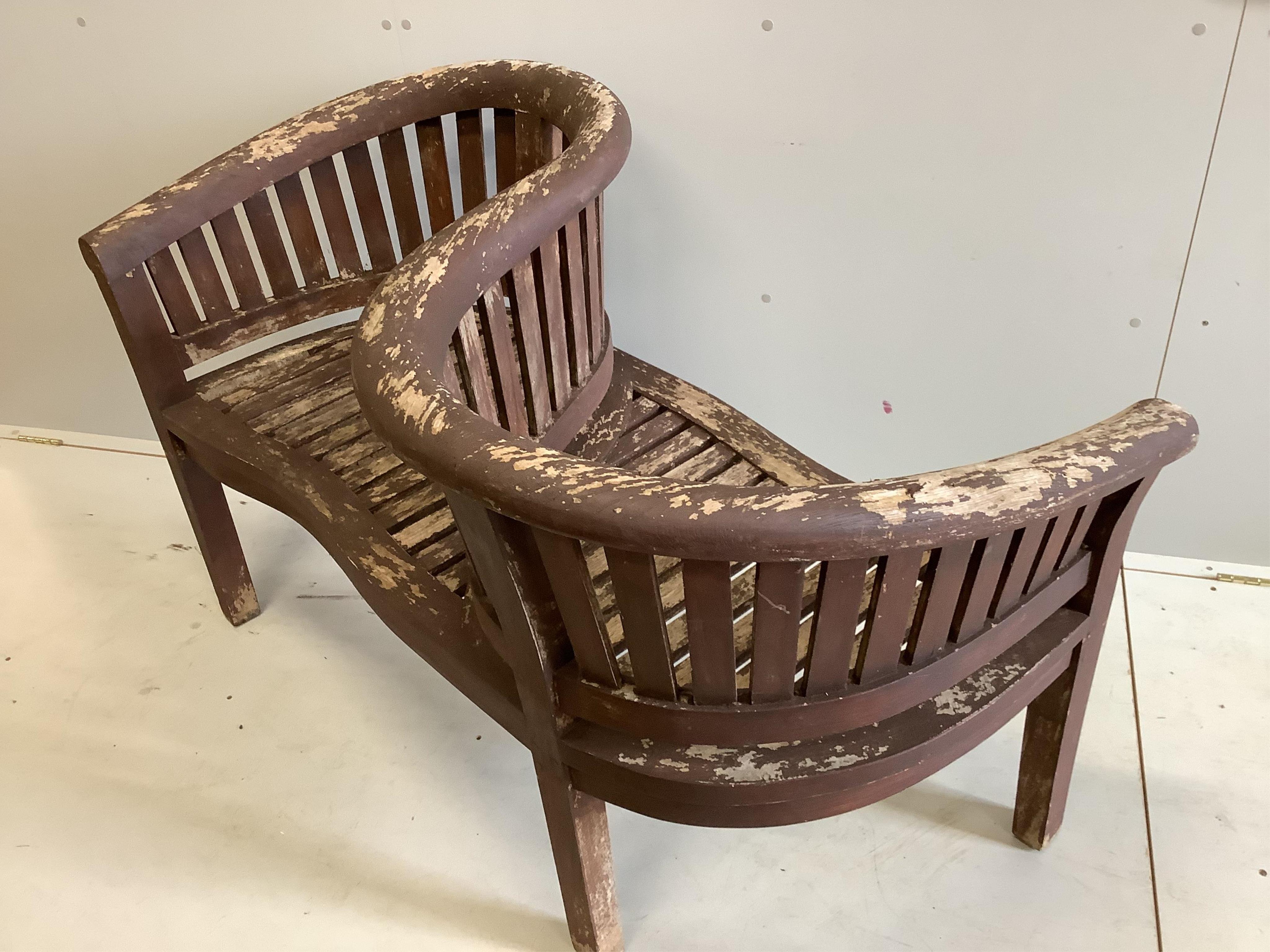 A stained teak garden 'banana' love seat, width 132cm, depth 58cm, height 86cm. Condition - fair